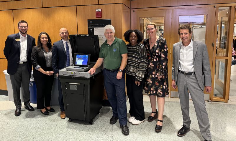 People standing with a voting machine.