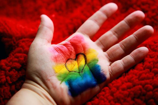Hand with rainbow chalk and black heart